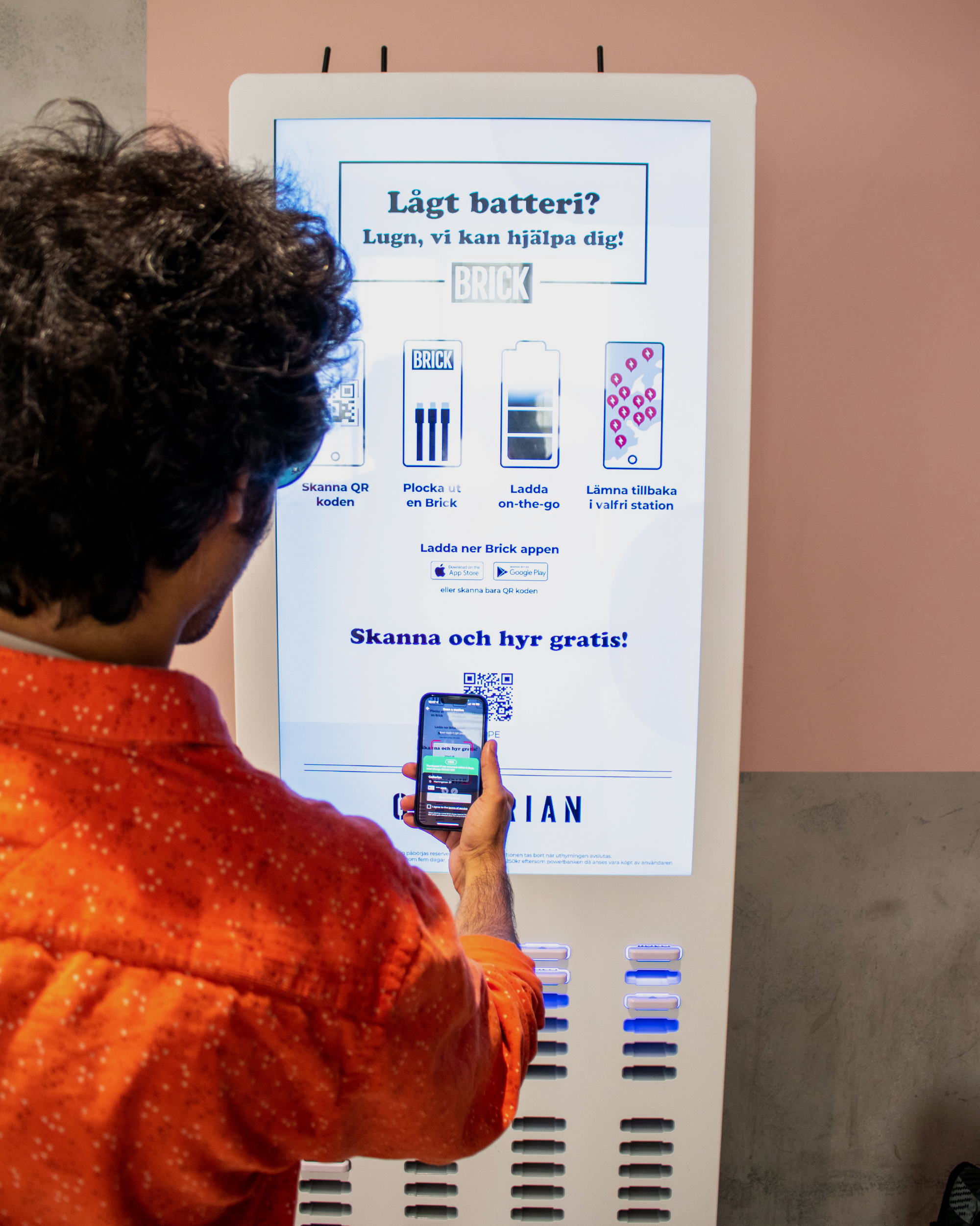 Picture of a person scanning the QR code with his phone on the screen of a charging station.