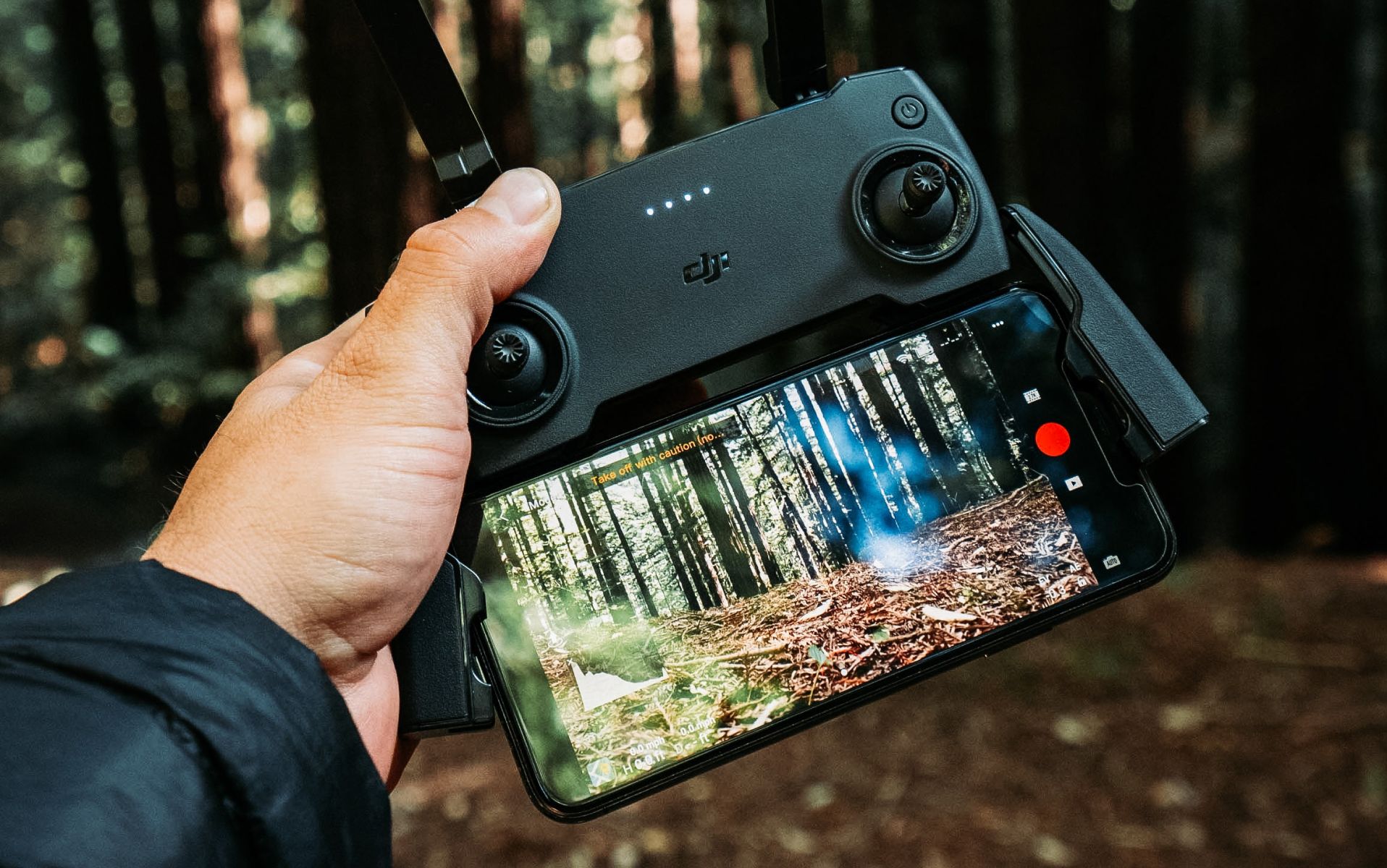 Hand holding a drone controller with an iPhone attached to it